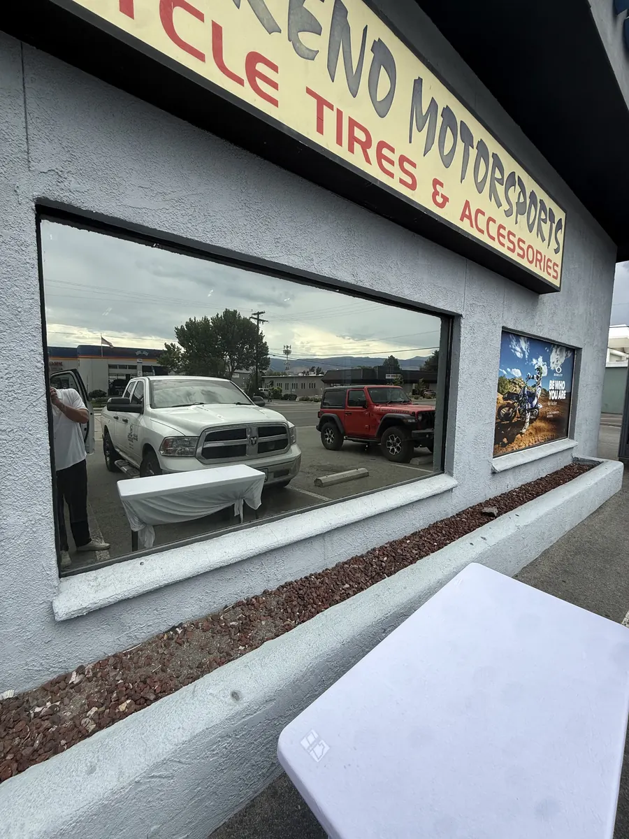 Reno Motorsports storefront window before graphics, reflecting the parking lot