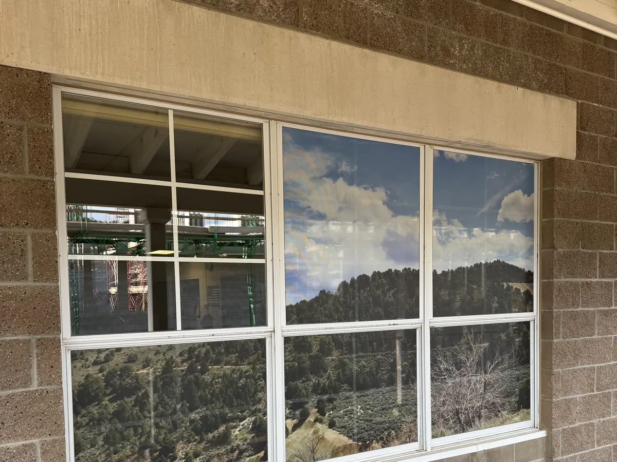 Virginia City High School library window from outside, partway through installing a printed hillside graphic